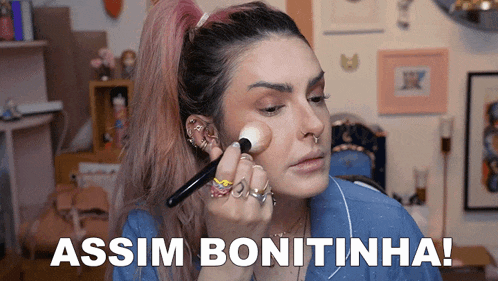 a woman is applying makeup with the words assim bonitinha written below her