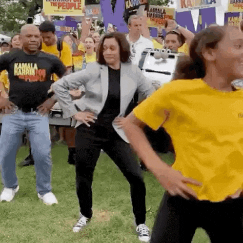 a group of people are dancing in front of a crowd wearing shirts that say kamala harris for the people .