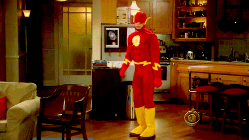 a man in a flash costume is standing in a living room