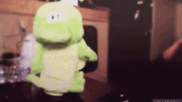 a green stuffed crocodile is sitting on a table .