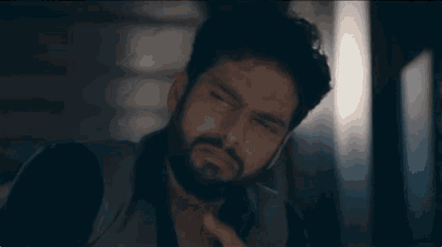 a man with a beard is making a funny face while looking at the camera .