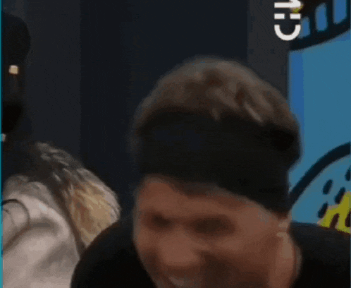a man wearing a black headband is laughing with his mouth open