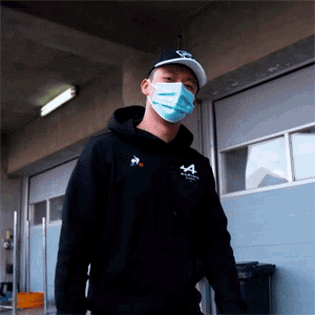 a man wearing a mask and a black hoodie with the letter a on the front