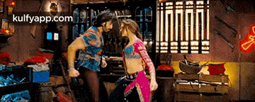 a man and a woman are dancing in a room with a neon sign .