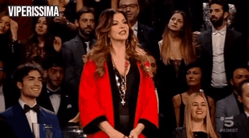 a woman in a red kimono is sitting in a crowd of people .
