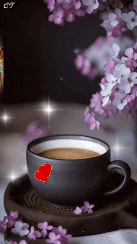 a cup of coffee with two hearts on it sits on a saucer next to purple flowers