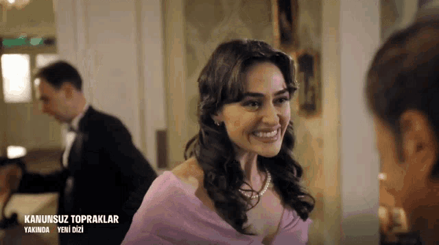 a woman in a pink dress is smiling in front of a sign that says " kanunsuz topraklar "