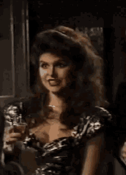 a woman in a black and silver dress holds a glass of wine