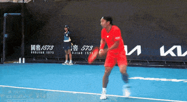 a man in a red shirt is playing tennis on a blue court