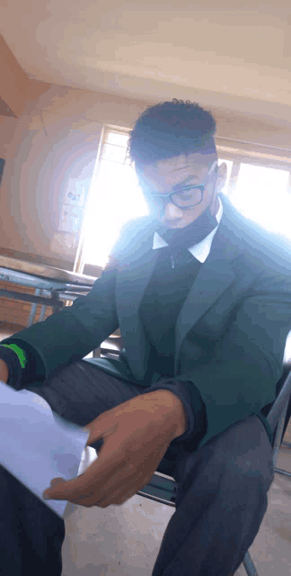 a man wearing glasses and a face mask sits in a classroom