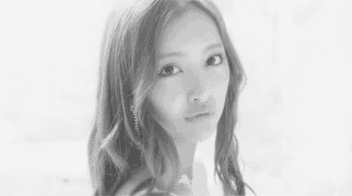 a black and white photo of a beautiful young woman looking at the camera .