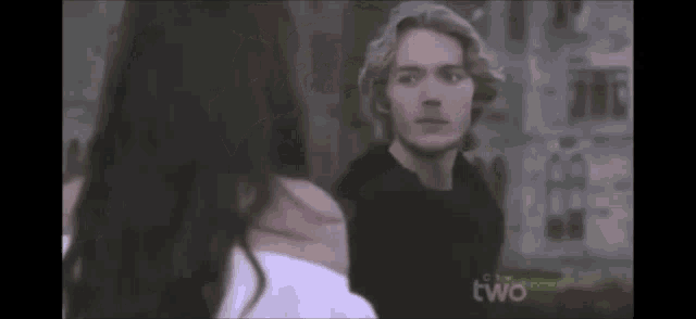 a man and a woman are standing next to each other and the word two is on the bottom of the screen .