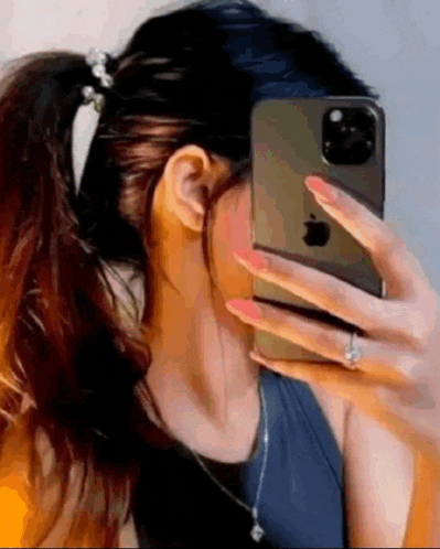 a woman is taking a picture of herself in the mirror with her phone .