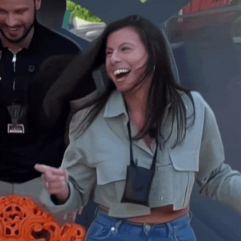 a woman wearing a crop top and jeans is laughing and pointing