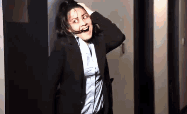 a woman in a suit is standing in a hallway with her mouth open .
