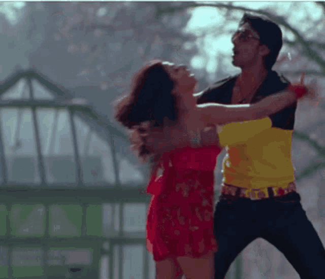 a man in a yellow shirt is dancing with a woman in a pink dress