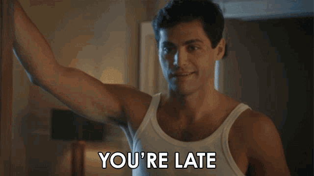 a man wearing a white tank top says you 're late