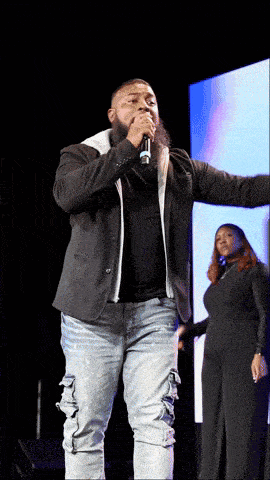 a man with a beard is singing into a microphone on a stage