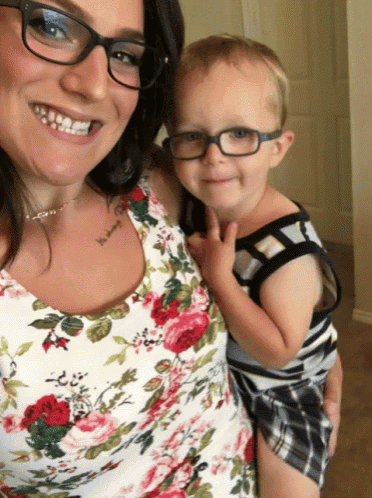 a woman wearing glasses is holding a young boy with glasses on