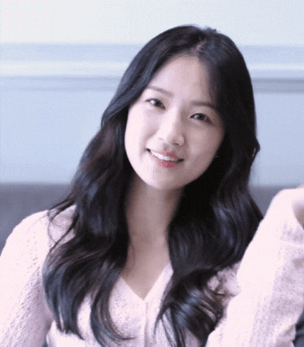 a woman with long black hair wearing a white sweater smiles for the camera