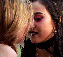 two women are kissing and one has a piercing in her lip .