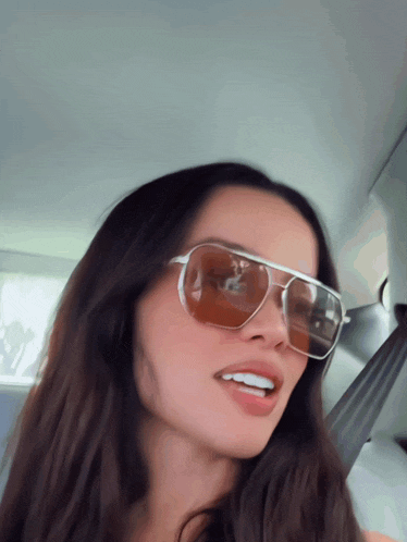a woman wearing a pair of sunglasses looks at the camera