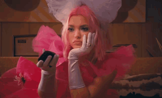 a woman wearing a pink dress and white gloves is sitting on a couch