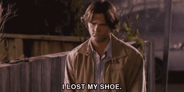 a man says " i lost my shoe " in front of a wooden fence