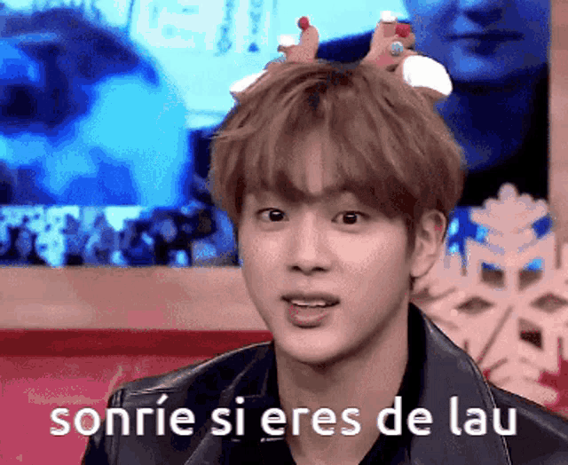 a young man wearing a reindeer headband smiles with the words sonrie si eres de lau above him