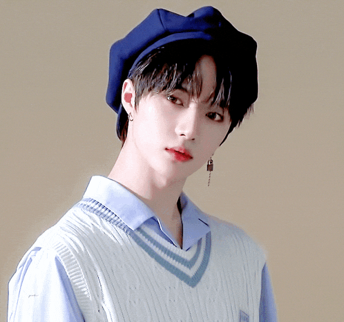 a young man wearing a blue hat and a sweater vest
