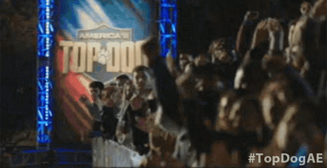 a crowd of people cheering in front of a sign that says " top dog "