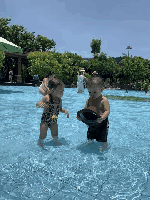 a boy and a girl playing in a pool