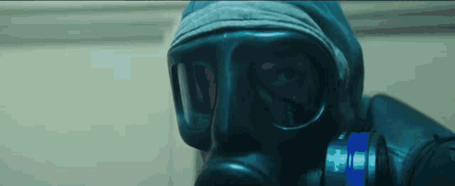 a man wearing a gas mask and goggles is standing in a room .
