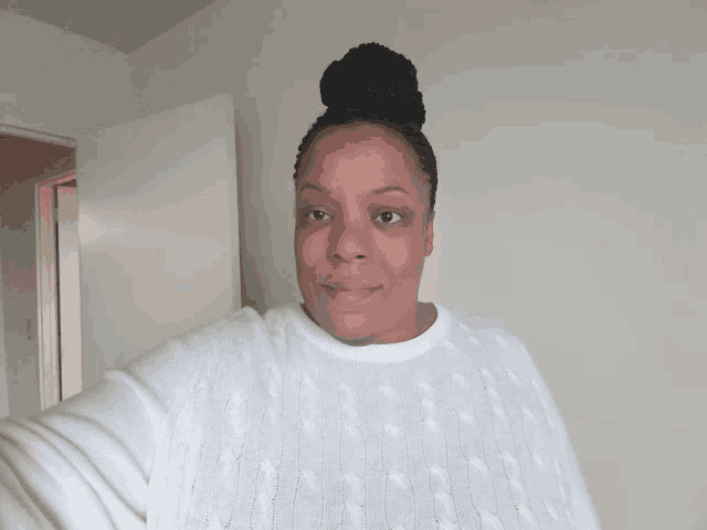a woman wearing a white sweater with a bun in her hair
