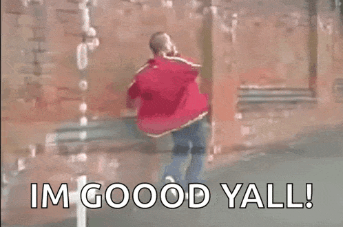 a man in a red jacket is standing in front of a brick wall with the words `` im good yall '' .
