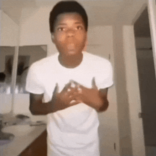 a young boy in a white shirt is standing in a bathroom with his hands on his chest