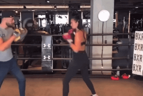 a man and woman are boxing in a gym with a sign that says bxr