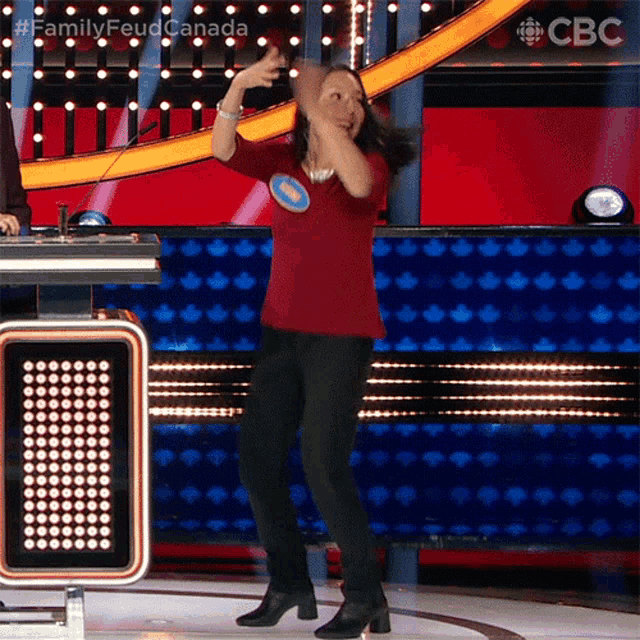 a woman in a red shirt is dancing on a stage with a cbs logo in the background