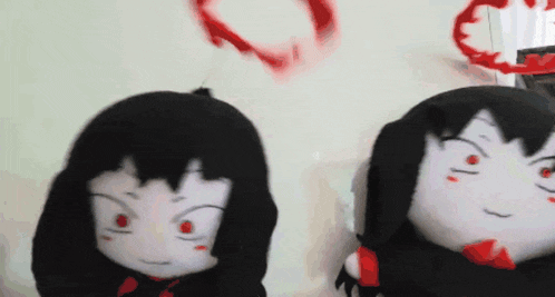 two stuffed dolls are sitting next to each other on a table .