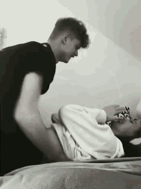a man is putting his hand on a woman 's stomach while they are laying on a bed .