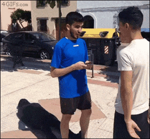 a man in a blue shirt talking to another man in a white shirt
