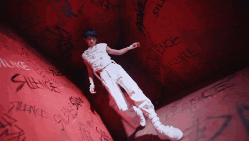 a person standing in front of a red wall with silence written on it