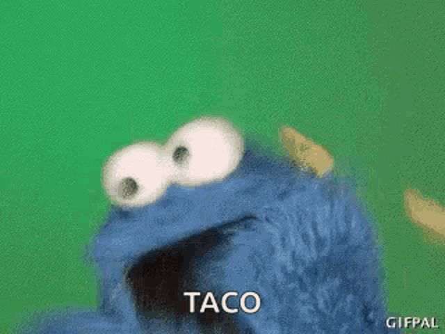 cookie monster from sesame street is eating a taco with its mouth open .