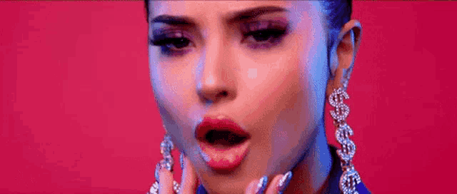 a close up of a woman 's face wearing a pair of earrings with dollar signs on them .
