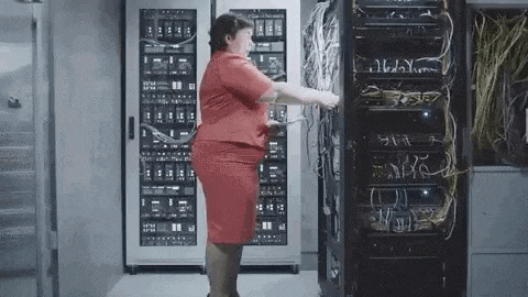 a woman in a red dress is standing in front of a server rack .