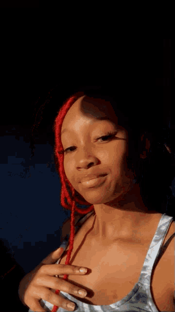 a woman with red dreadlocks is smiling in the dark