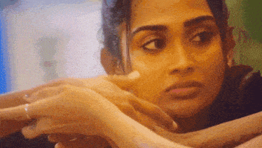 a close up of a woman 's face with her hand on her shoulder