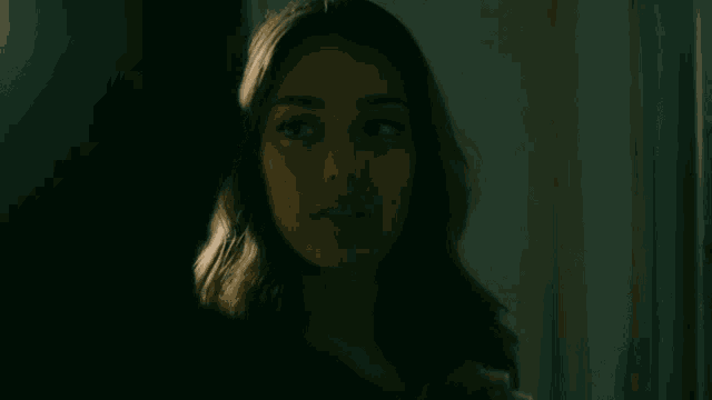a woman is looking at herself in a mirror in a dark room