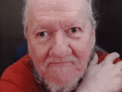 a man with a beard and a red shirt is making a face