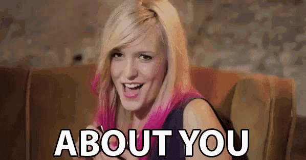 a woman with pink hair is sitting on a couch and smiling with the words about you above her
